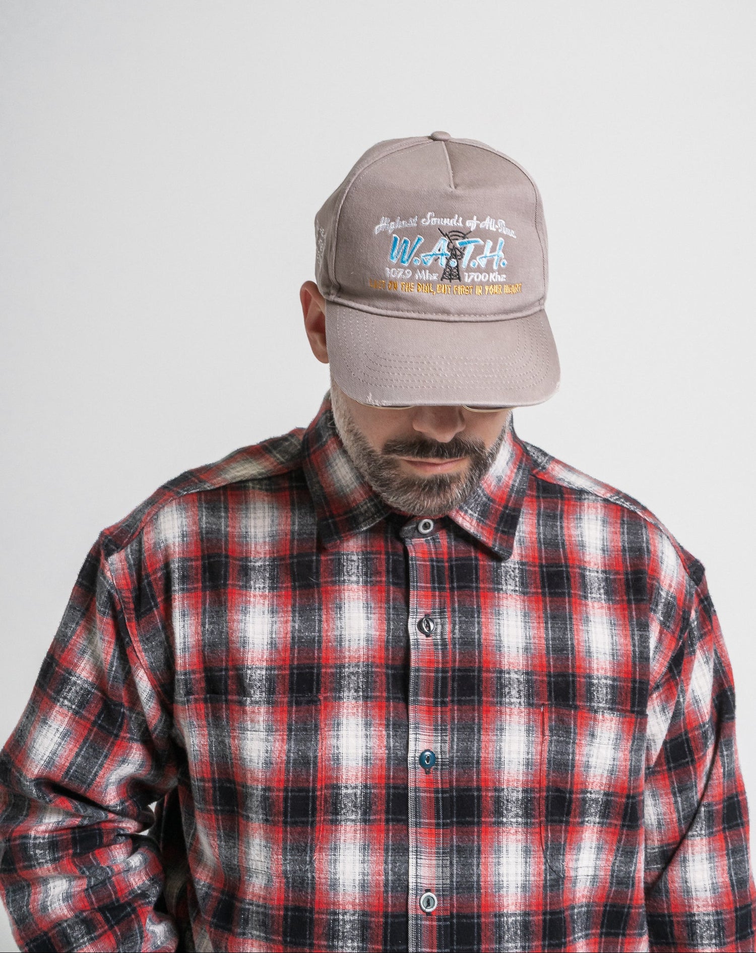 Man wearing a plaid shirt and a cap with text on a plain background