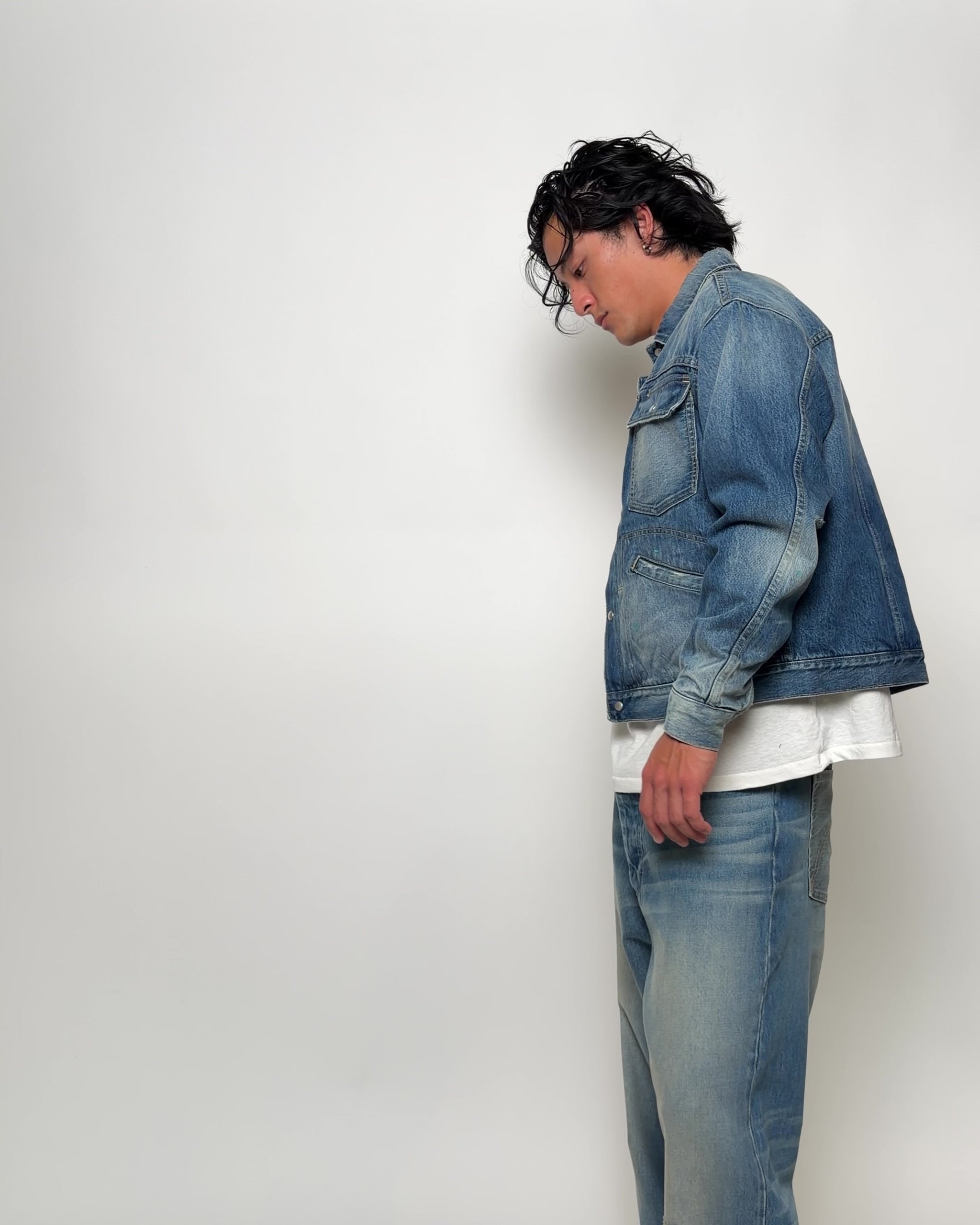 Video of man wearing distressed and washed denim jacket and jeans in studio